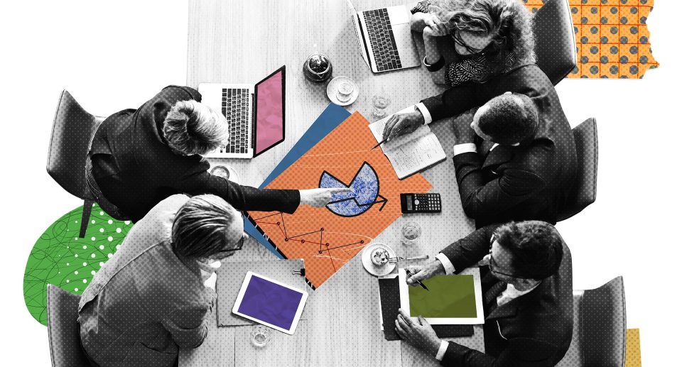 Top view of a creative agency team discussing brand strategy with laptops, tablets, and marketing charts on a conference table